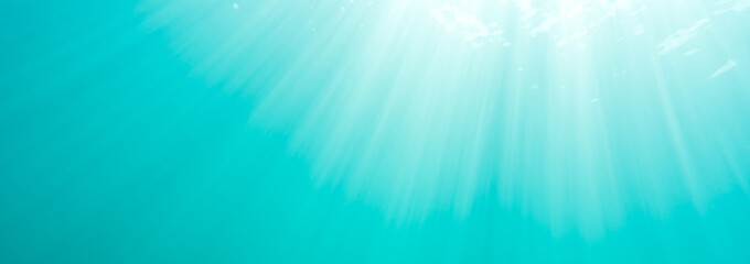 Sun rays shine through the water surface in summer