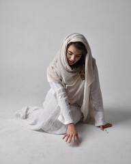 Full length portrait of young woman wearing classical white gown and a head covering veil in...