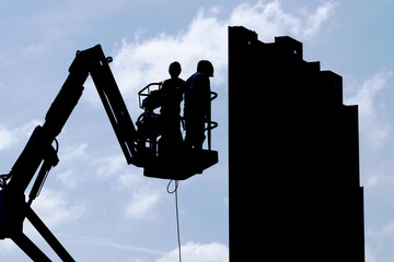 silhouette ouvrier dans une nacele sur un chantier de batiment