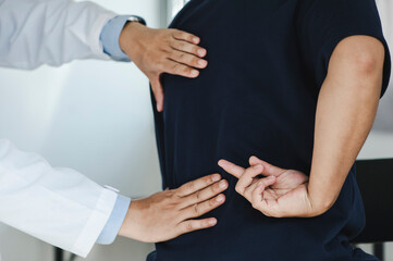 Closeup of a male Doctor or physiotherapist is doing stretching for a patient in the clinic for examining treating injured of back and Doing the Rehabilitation therapy pain