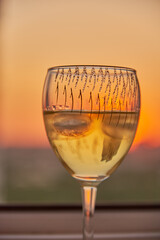 A glass of wine on the windowsill against the background of the sunset.
