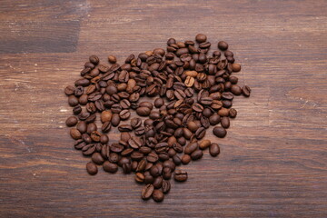 Black coffee grains lie on a brown wooden table, background image