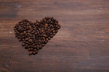 Black coffee grains lie on a brown wooden table, background image