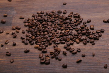 Black coffee grains lie on a brown wooden table, background image