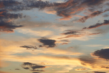 Beautiful evening blue sky at sunset with flaming bright light clouds. A warm summer evening at sunset. Bright sunset.