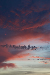 Naklejka premium Beautiful evening blue sky at sunset with flaming bright light clouds. A warm summer evening at sunset. Bright sunset.