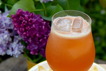 Scotch based cocktail with ice and lilac flower background