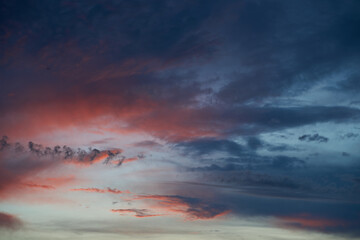 Beautiful evening blue sky at sunset with flaming bright light clouds. A warm summer evening at sunset. Bright sunset.