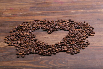 Heart shape made from coffee beans on wooden surface. - Powered by Adobe