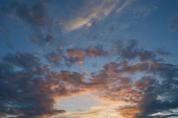 Beautiful evening blue sky at sunset with flaming bright light clouds. A warm summer evening at sunset. Bright sunset.