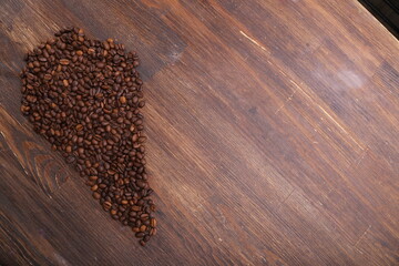 Heart shape made from coffee beans on wooden surface.