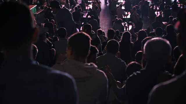 People watching football in a public place at night, celebrating and clapping
