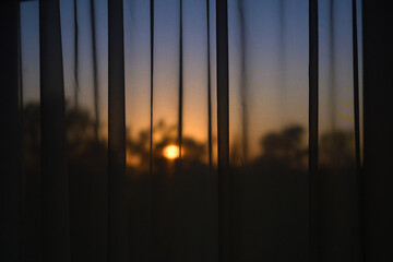 The sunset through the tulle on the window. Contour evening dusk light.