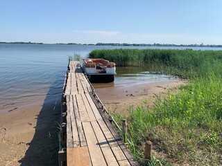 Beautiful picturesque outdoor scene of an old wooden pier sticking out into the calm water of Volga...