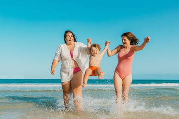Cheerful mothers swinging son over sea water