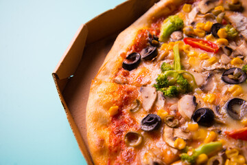 Baked pizza with ham, corn, broccoli, olives, tomato. Unhealthy fastfood junk food favorites by young people.