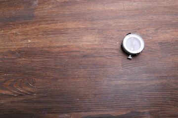 Old compass on brown wooden table background.