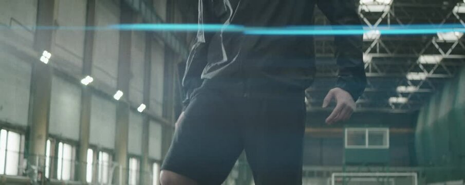 Tilt up anamorphic shot of professional soccer athlete in sportswear stretching quads before training on indoor field