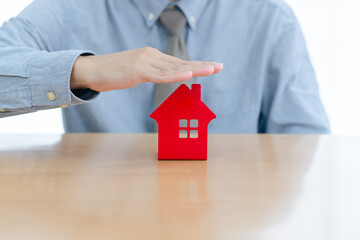 businessman hands protecting red house model residential concept of home protection, insurance, real estate investment. with a white background