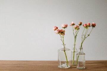 Pink roses in glass bottles on a wooden table