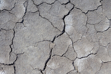 A dry, lifeless, barren clay land cracked in the African desert during global warming and climate change. A hot surface during drought is destroyed, eroded and textured. Copy space, background.