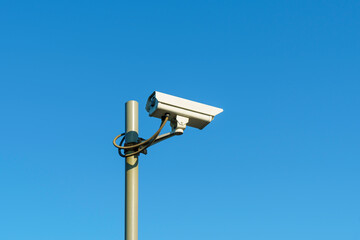 CCTV camera on pole on clear blue sky background for law and order
