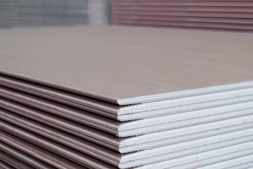 The stack of Plasterboard fire resistant gypsum board cardboard surface Panel Type DF for indoor concrete walls prepared for construction, selective focus - obrazy, fototapety, plakaty