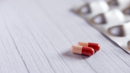 Red-White medicine capsules on wooden white table background with copy space. Medicine concept.