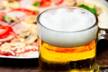Glass of beer close up on pizza background.