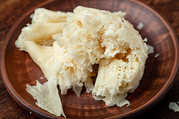 Hard cheese sliced chips on a clay plate on a wooden background.