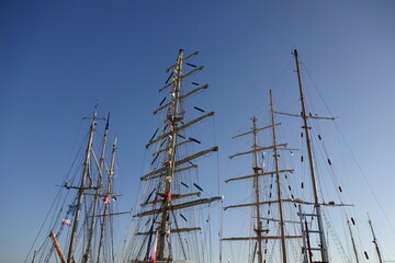 Close up view of wooden masts with many color signal flags on a clear blue sky background. Marine...
