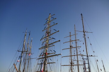 Close up view of wooden masts with many color signal flags on a clear blue sky background. Marine festival of tall ships - Sail Tallinn 2021. July, Estonia, Europe