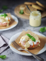 Egg benedict sandwiches - muffin with poached egg, ham and hollandaise sauce