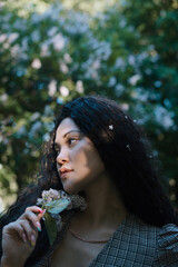 Beautiful asian female standing in front of blossom trees with flowers in her hand