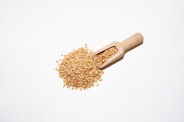 Pile of golden linseed on wooden spoon on white background