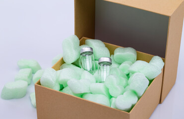 The photo shows an opened package with styrofoam snippets and two vaccine vials isolated on white background
