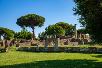 Fototapeta na wymiar Ostia Antica site Rome, ruins of marble columns with brick buildings from the imperial era in Ostia Antica archaeological park in summer with blue sky. Rome Italy, Europe.