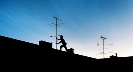 silhouette of an aerialist repairing a television antenna