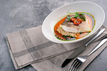 Fried fish fillet of halibut on a plate with tomato sauce. Cod steak or white fish with sauce and herbs