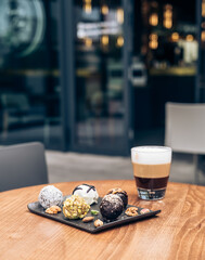 Few Different Protein Balls and Layered Latte in a Transparent Glass on the Table in a Coffee Shop Outdoors