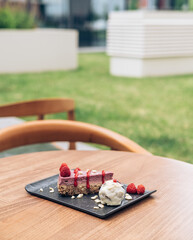 A Slice of Raspberry Cake on Black Plate in an Outdoor Coffee Shop