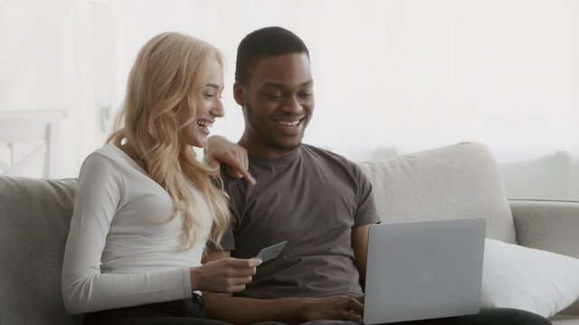 Diverse Couple Using Laptop And Credit Card Shopping Online Indoor
