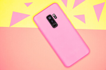 Pink phone on the pink and yellow background with paper triangles