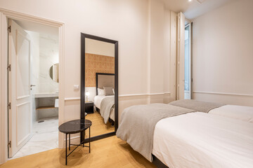Bedroom with two beds and bathroom en suite, large full-length mirror in vacation rental apartment