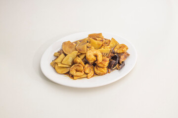 Typical and delicious recipe of sautéed prawns with bamboo and Chinese mushrooms with soy sauce on a white plate