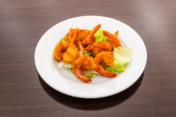 Chinese recipe of peeled shrimp in batter with salt and pepper lettuce on white plate
