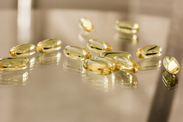 Transparent yellow capsules Omega, Omega 3, fish oil and their reflections on glass background, table