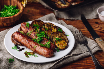 Pork Sausages Baked with Eggplant Slices on White Plate Garnished with Fresh Dill