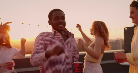 Company of multicultural happy friends buddies socializing outdoors, dancing at rooftop party celebration, enjoying life and youth.