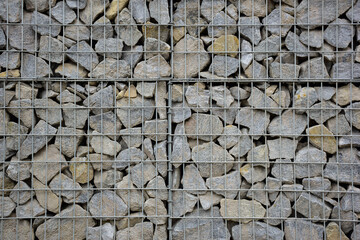 A large fence of many stone boulders supported by a stone trellis for the entire frame